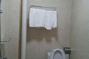 Un baño con inodoro, toallero con toallas y zona de ducha.