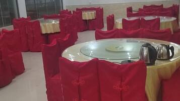 A room with round tables covered with red tablecloths and chairs, arranged in a circular pattern.