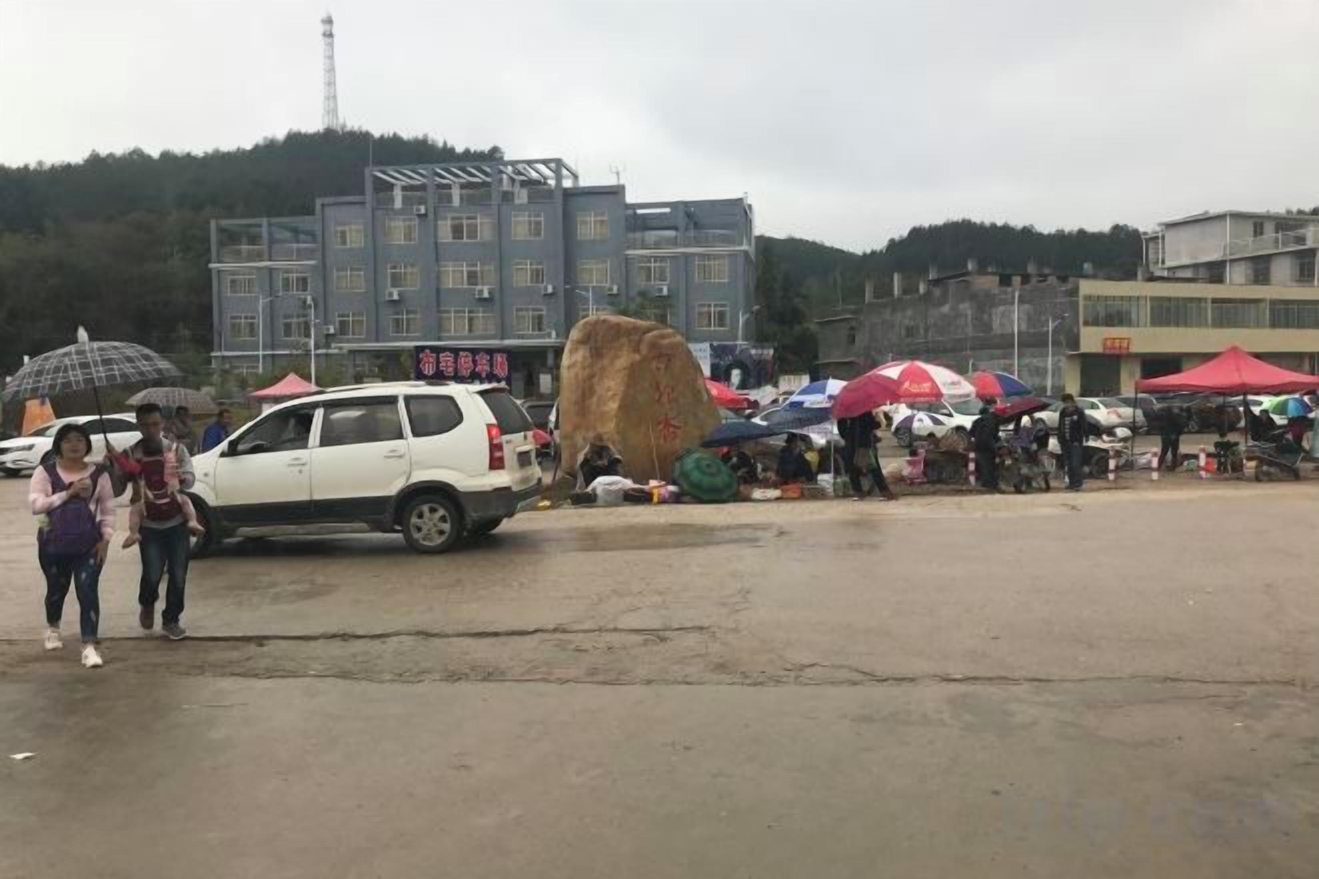 An outdoor market with tents and a white car.