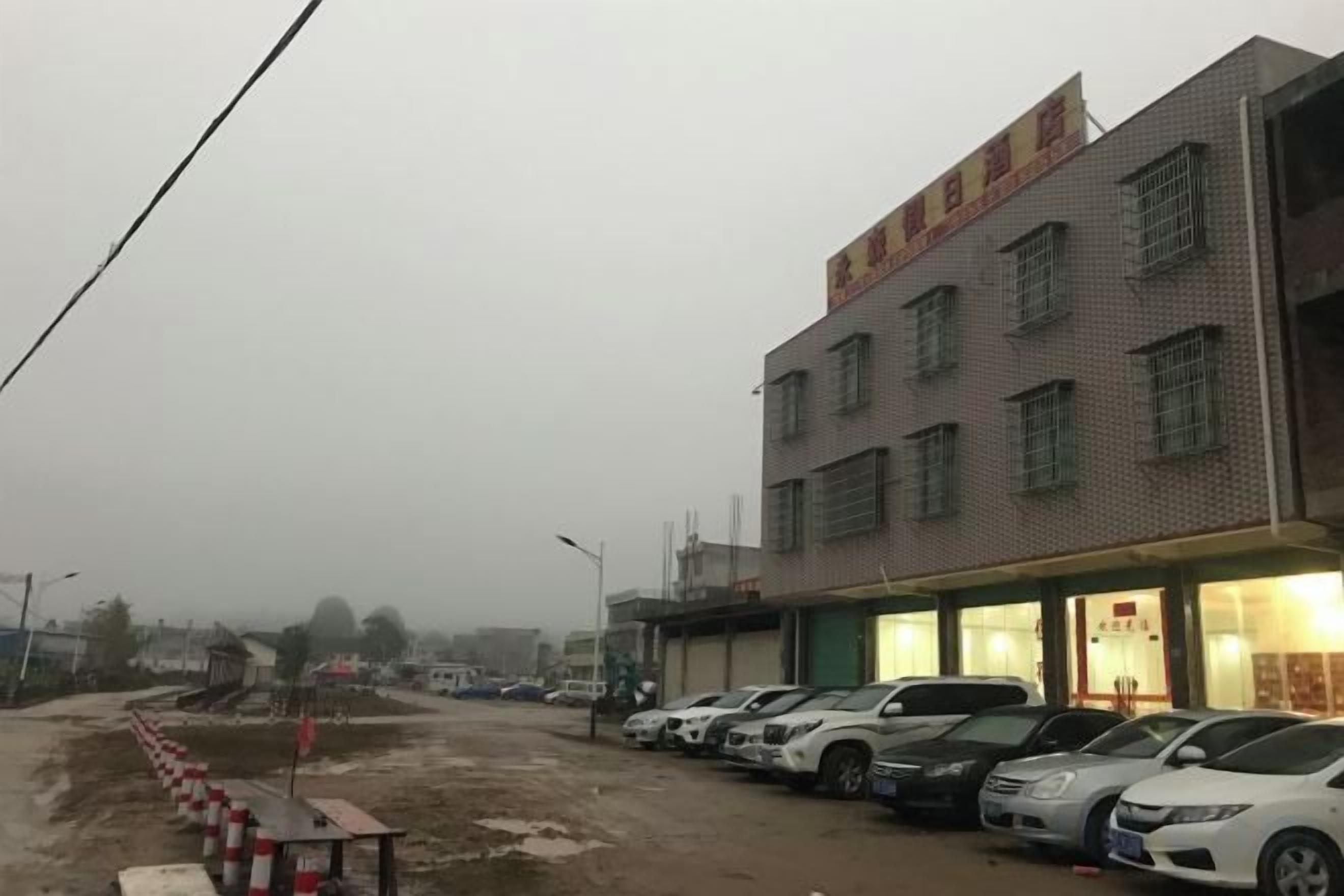 A building with multiple floors and a parking lot with several cars.