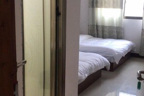 Une pièce avec un lit, une porte et une fenêtre avec des rideaux.