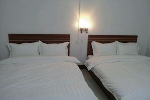 Ein Hotelzimmer mit zwei Betten, einem Holzkopfteil und einer Wandleuchte.
