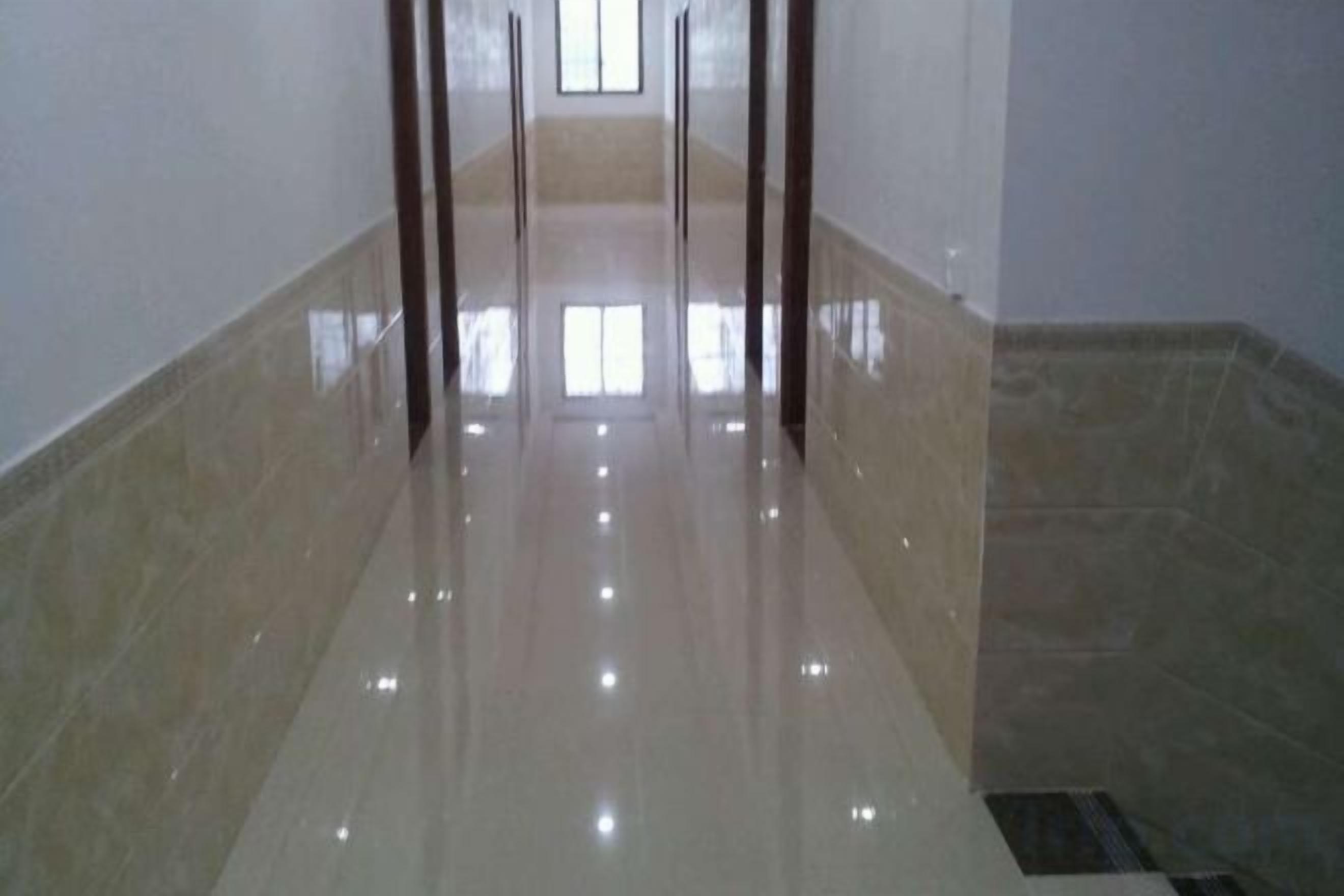 A hallway with a shiny floor, leading to a door at the end.