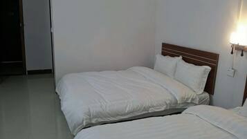 A hotel room with two beds, a wooden headboard, and a wall-mounted light fixture.