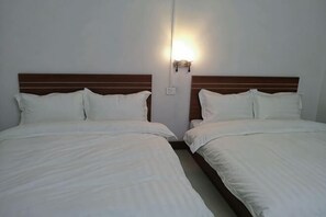 Una camera d'albergo con due letti, una testiera in legno e un punto luce a parete.