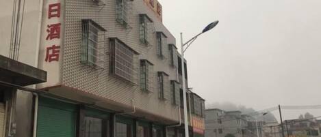 A building with multiple windows and a green door, likely a hotel or similar establishment.