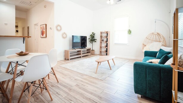 Uma sala de estar moderna com área de jantar, um sofá, uma TV e um ventilador de teto.