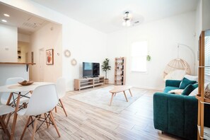 Una sala de estar moderna con comedor, sofá, televisor y ventilador de techo.