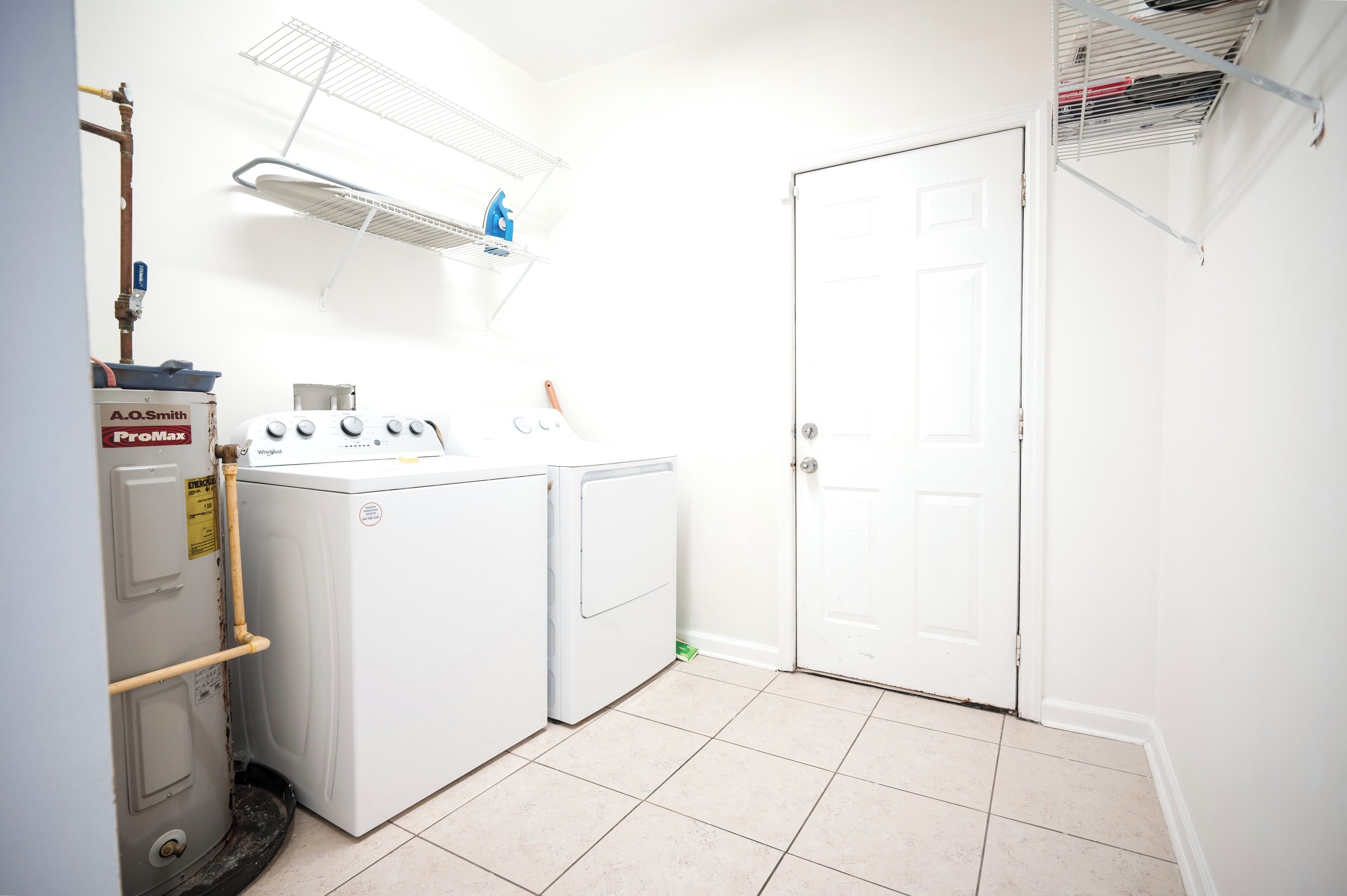 A laundry room with a washing machine, dryer, and ProMax water heater.