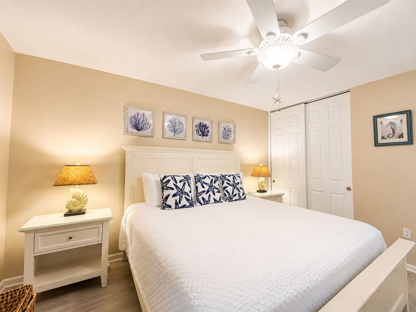 A bedroom with a bed, two bedside tables, a ceiling fan, and wall art.