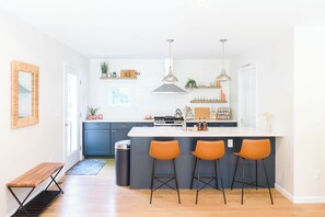 A modern kitchen with a central island, bar stools, and pendant lighting. - 5 Min to Downtown Warwick, Wineries, Breweries, Hikes, Shops, & Greenwood Lake! (Warwick)