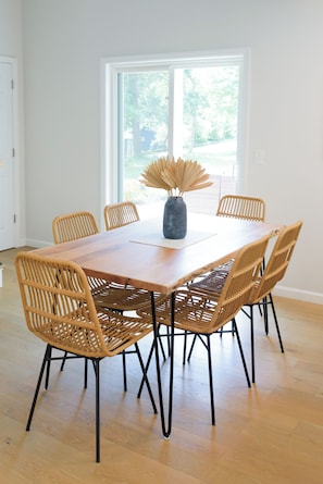 Een eetruimte met een houten tafel en zes rieten stoelen.