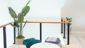 A modern interior with a balcony, wicker ottomans, a marble table, and a potted plant. - 5 Min to Downtown Warwick, Wineries, Breweries, Hikes, Shops, & Greenwood Lake! (Warwick)