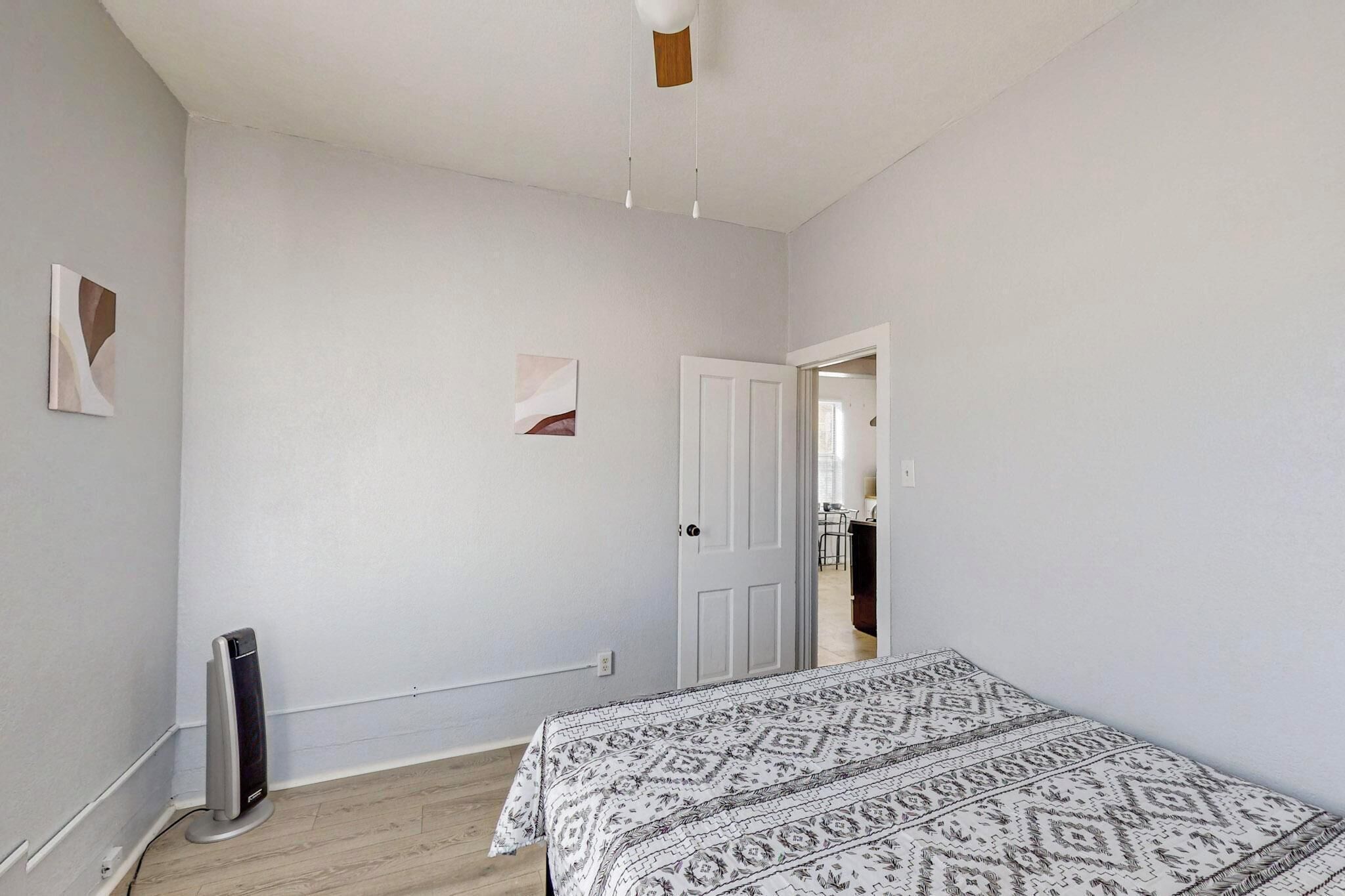 Une chambre à coucher avec un lit, un radiateur et une porte donnant sur une autre pièce.