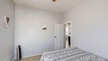 Une chambre à coucher avec un lit, un radiateur et une porte donnant sur une autre pièce.