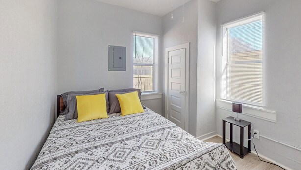 A bedroom with a bed, two windows, a door, and a ceiling fan. - Charming 1-bedroom house in marvelous Albuquerque with WiFi, AC (albaquerque)