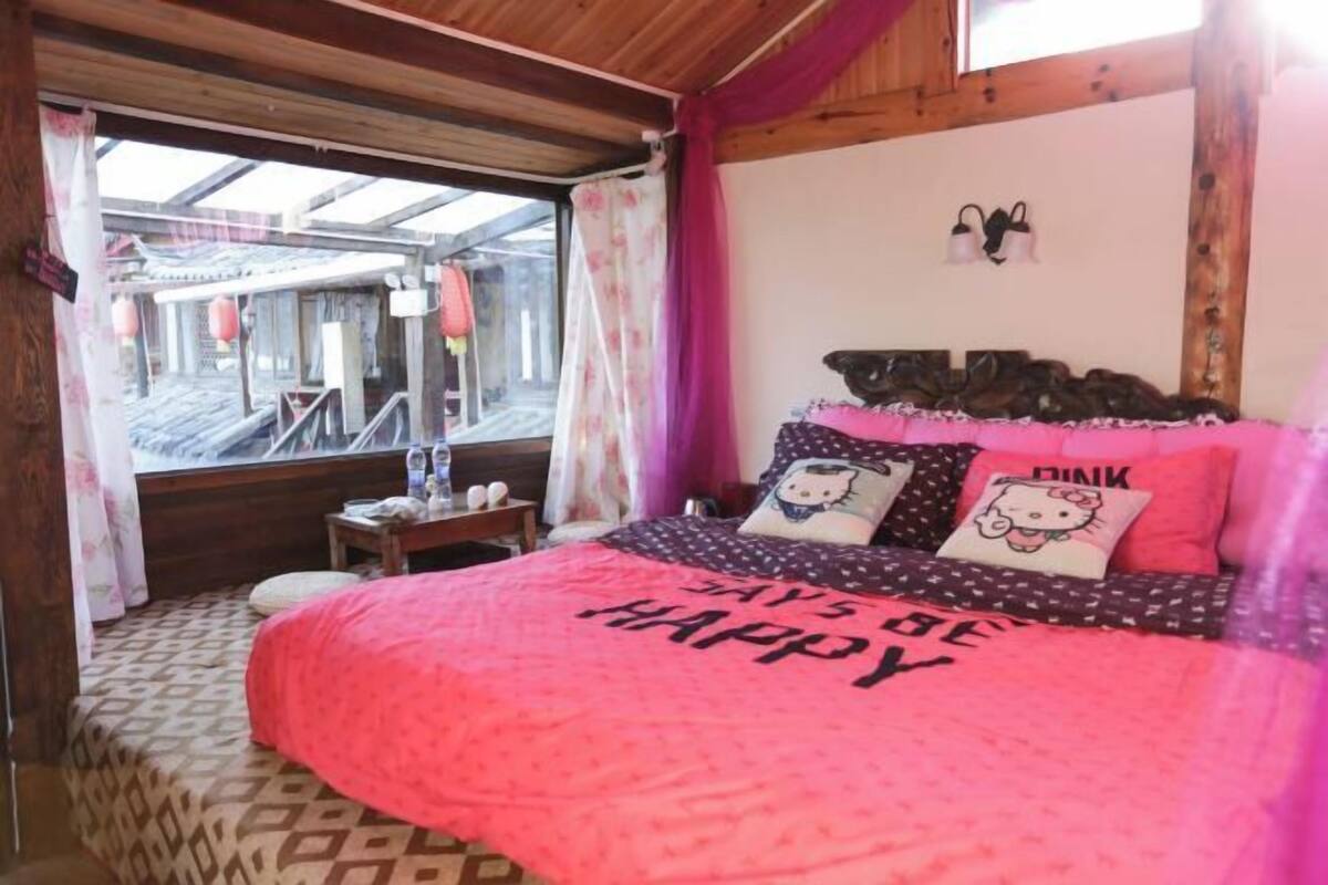 Un dormitorio con una cama grande, una ventana y techo de madera.