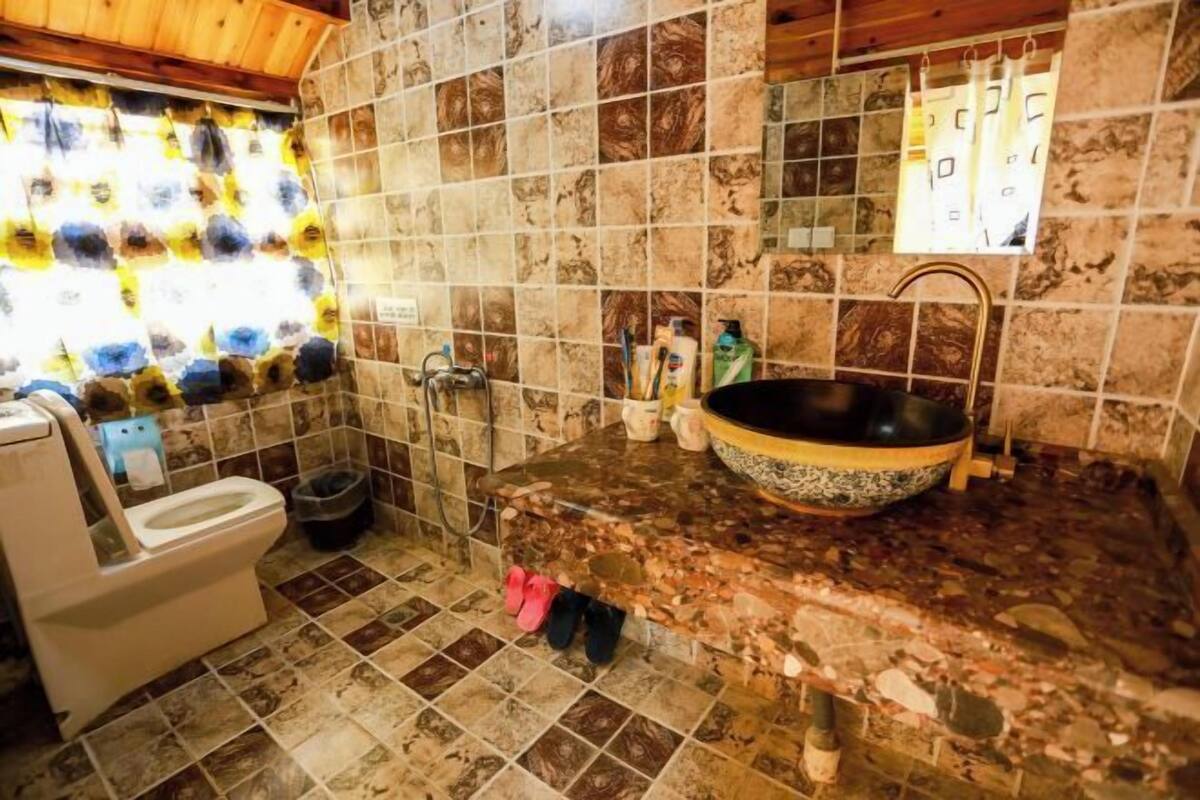 Un baño con inodoro, lavabo, paredes de azulejos y zona de ducha.