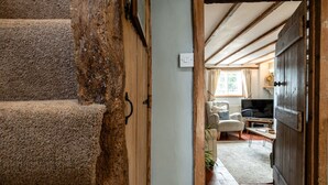 A rustic staircase leading to a living room with a sofa, a coffee table, and a television. - Poppy Cottage - Cosy 2BD Home, Perfect For Family (Clifford Chambers)