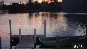 A calm lake at dusk with a wooden dock and a small boat. - POUSADA DAS COLÔNIAS ILHA DA GIJÓIA (Rio de Janeiro)