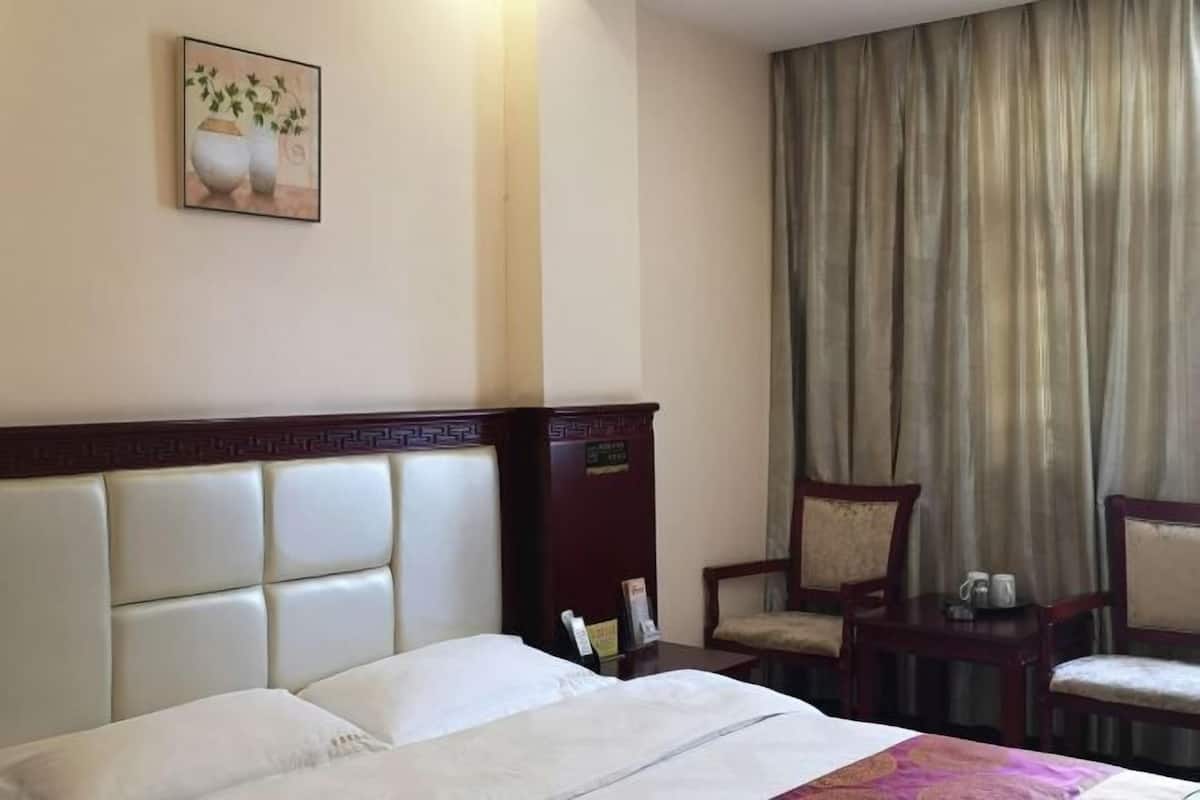 Habitación de hotel con cama, una silla, una mesita y un cuadro en la pared.