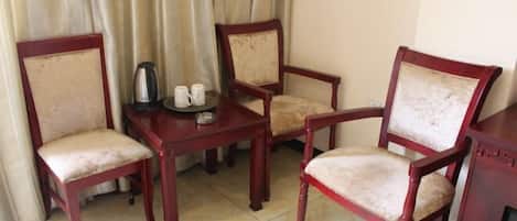 Una habitación con una mesa de madera y cuatro sillas, una tetera y dos tazas sobre la mesa.
