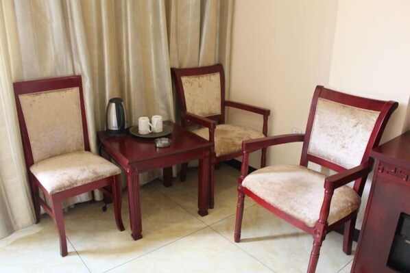 A room with a wooden table and four chairs, a kettle, and two cups on the table. - Jinquan Business Hotel (Jinping)