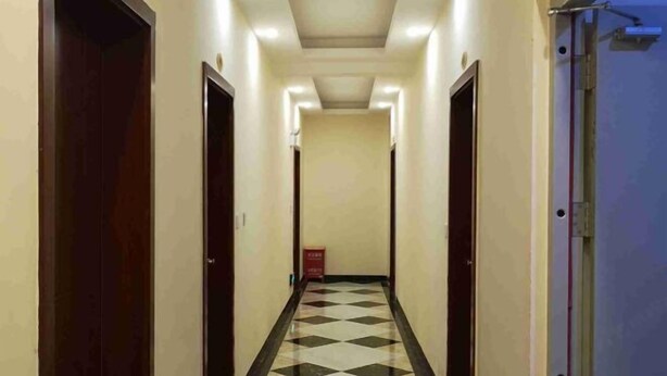A hotel hallway with a checkered floor, doors on both sides, and a red sign on the wall. - Jinquan Business Hotel (Jinping)