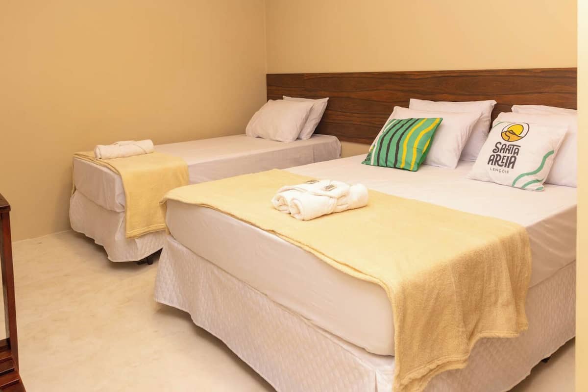 A hotel room with two single beds, each with a yellow blanket and white pillows.