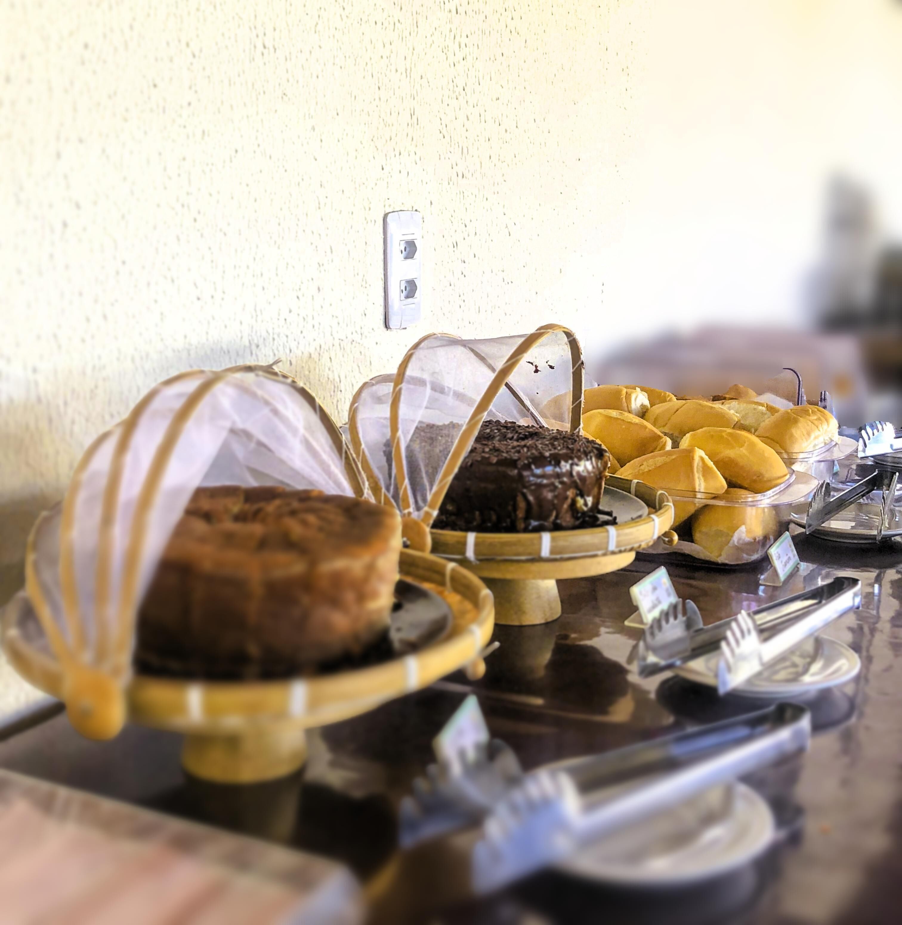 A buffet table with various baked goods and a power outlet on the wall.