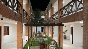 A courtyard with a seating area, brick walls, and a palm tree. - Santa Areia Lençóis Pousada (Santo Amaro do Maranhão)