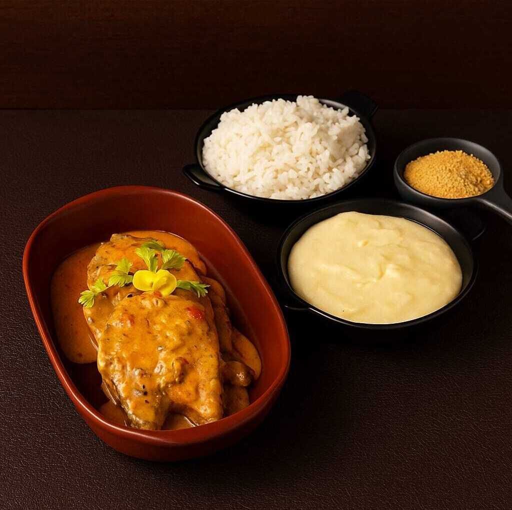Un plato con pollo, arroz blanco y puré de papas.