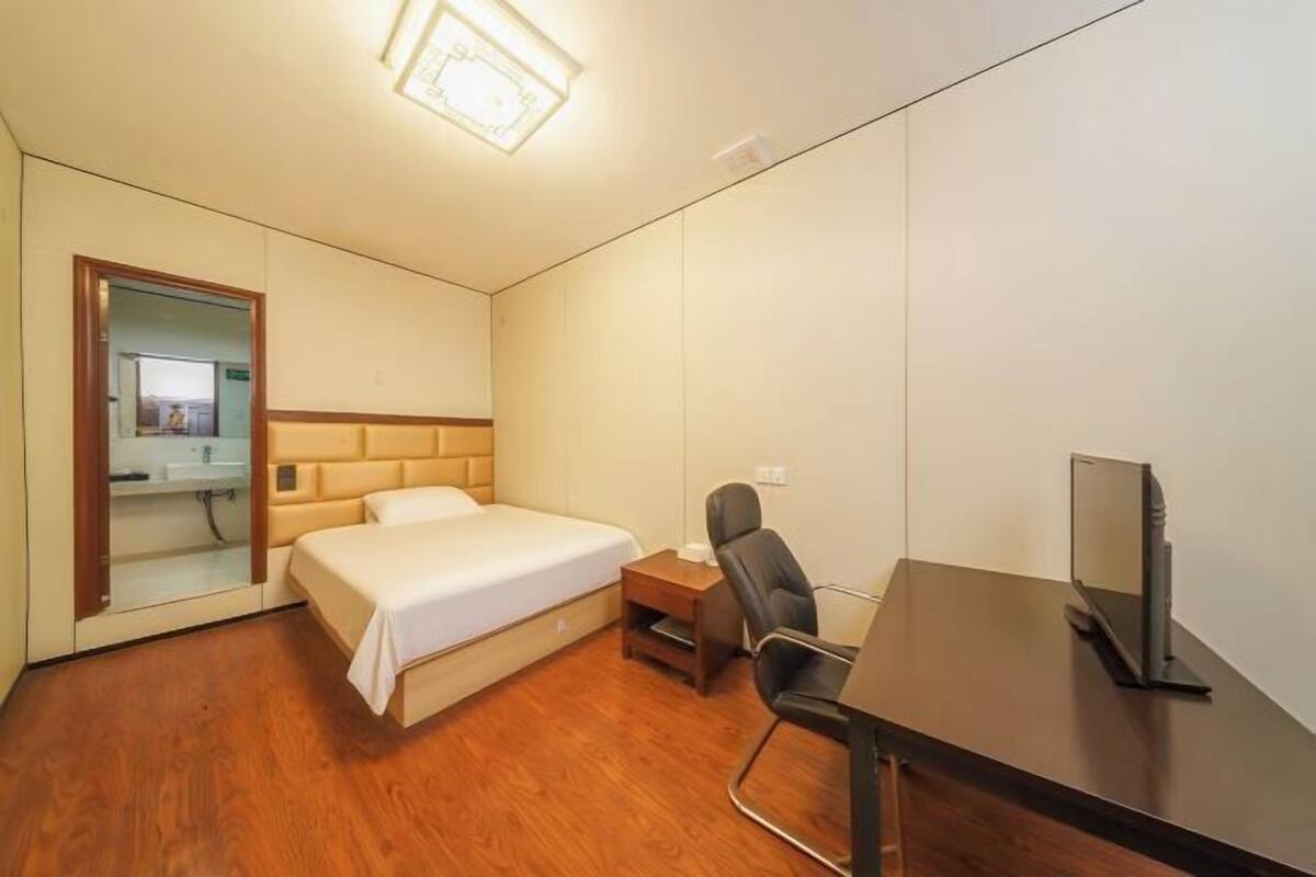 Una habitación de hotel con cama, escritorio, silla y televisor.