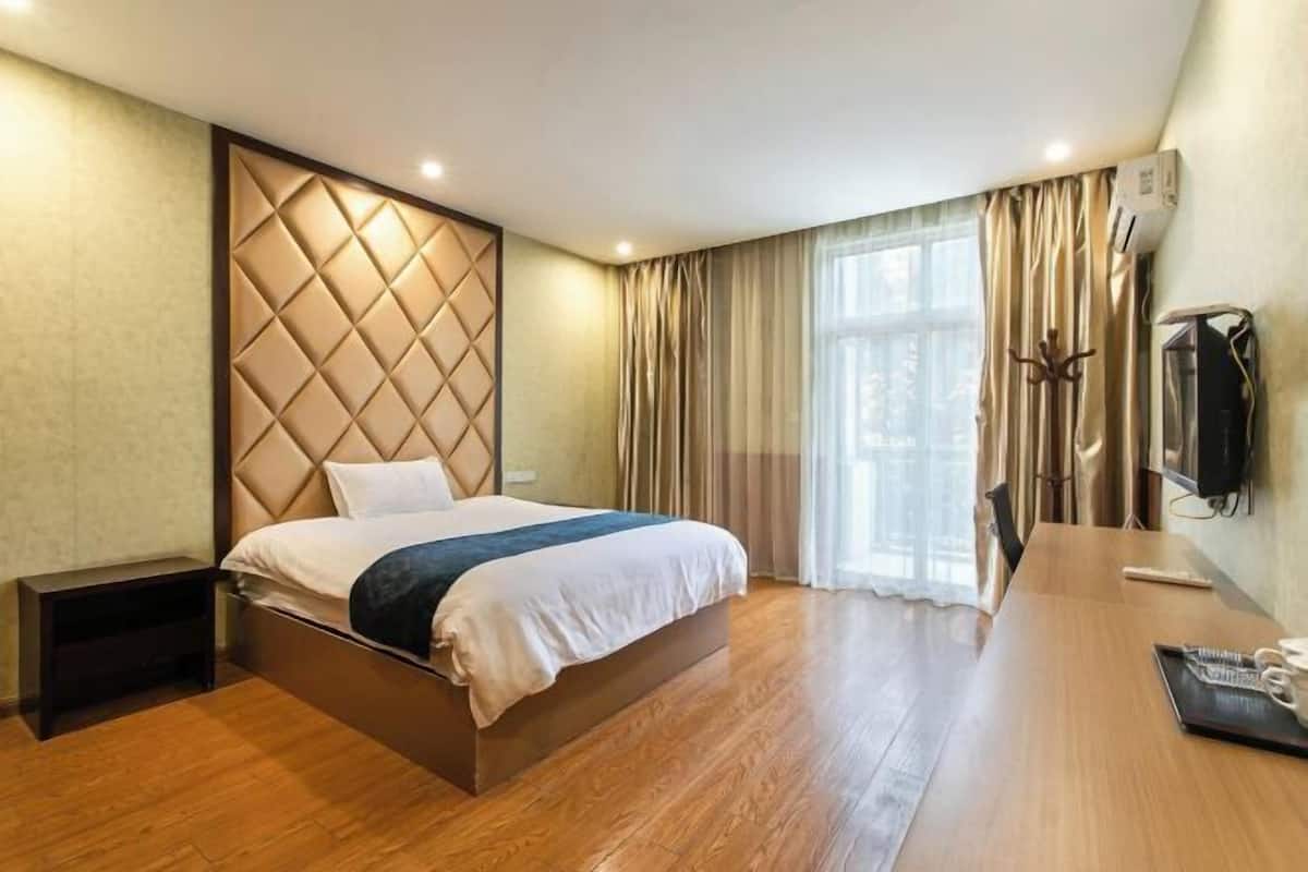 Una habitación de hotel moderna con una cama grande, un escritorio de madera y un televisor.
