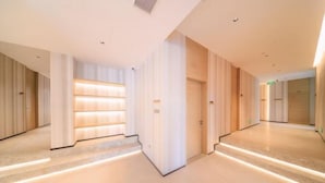 Un corridoio moderno di un hotel, con pavimento chiaro, rivestimenti in legno e una fila di porte.