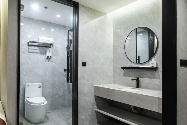 A modern bathroom with a glass-enclosed shower, a white toilet, a round mirror above a sink, and a towel rack. - Yijia Business Hotel (Taizhou)