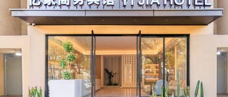 The entrance to Yi Jia Hotel with a clear glass facade, a modern design, and a visible indoor seating area.