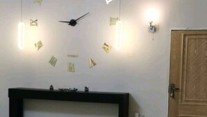 Ein Zimmer mit einer an der Wand befestigten Uhr, einer Holztür und einem schwarzen Konsolentisch.