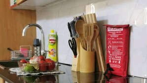 Eine Küche mit Holzschränken, einer schwarzen Arbeitsplatte und diversen Küchengeräten und -utensilien.