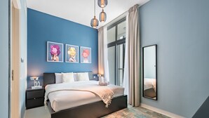 A modern bedroom with a large bed, a nightstand, a mirror, and artwork on the wall.