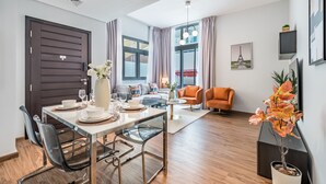 A modern living room with a dining area, featuring a sofa, a coffee table, and a dining table set for four.