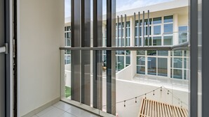 A modern interior with large windows, a balcony, and a view of a building with multiple windows.