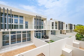 A modern multi-story building with large windows, a flat roof, and a minimalist design. - Charming 3BR Townhouse with Study Room in Damac Hills 2 Centaury by Deluxe Holiday Homes (Dubai)