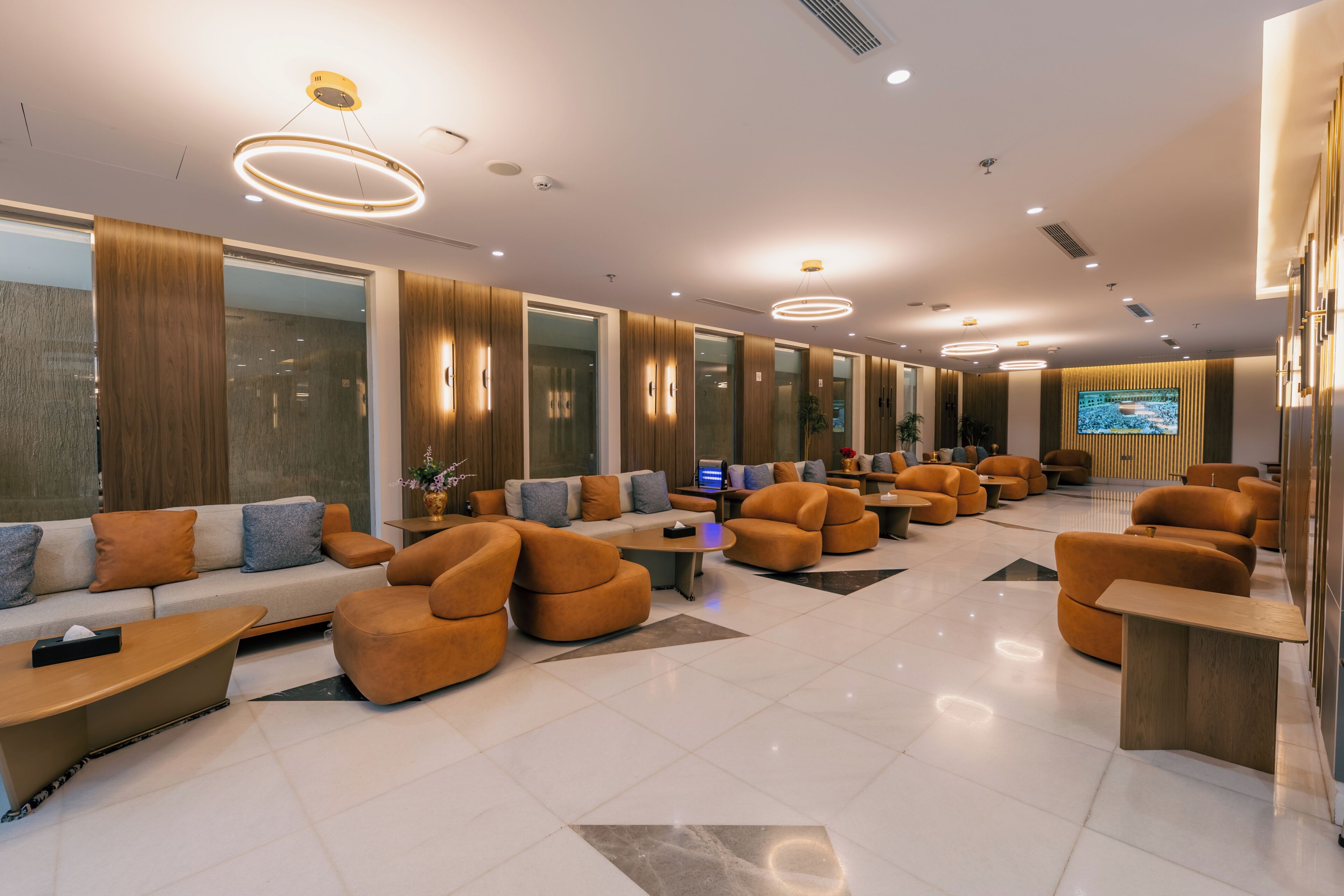 Un hall d’entrée moderne avec des canapés, des fauteuils et un grand écran.