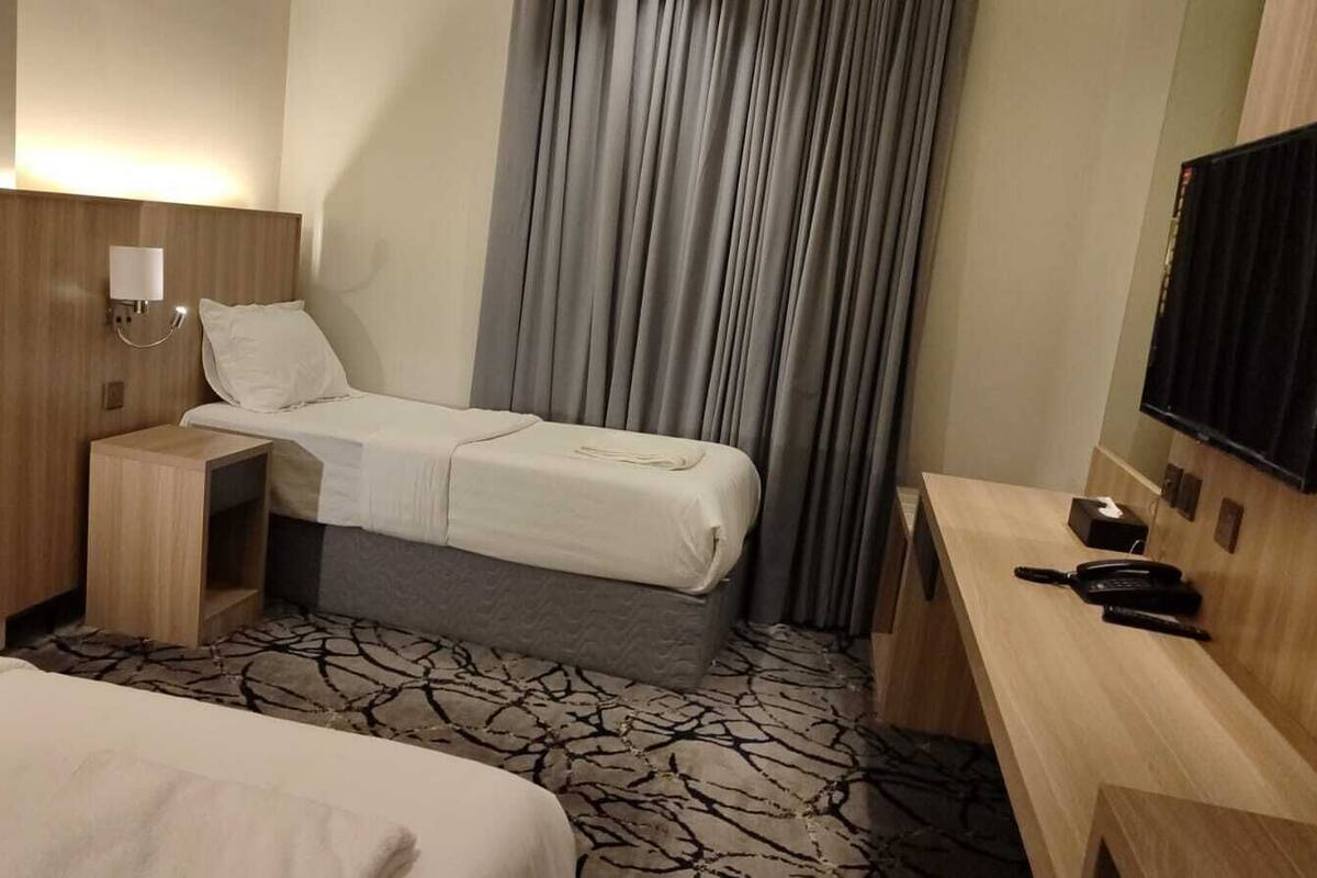 A hotel room with a bed, bedside table, lamp, and a flat-screen TV mounted on the wall.