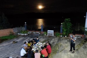 Un groupe de personnes dînant en plein air, la nuit, avec vue sur l’eau.