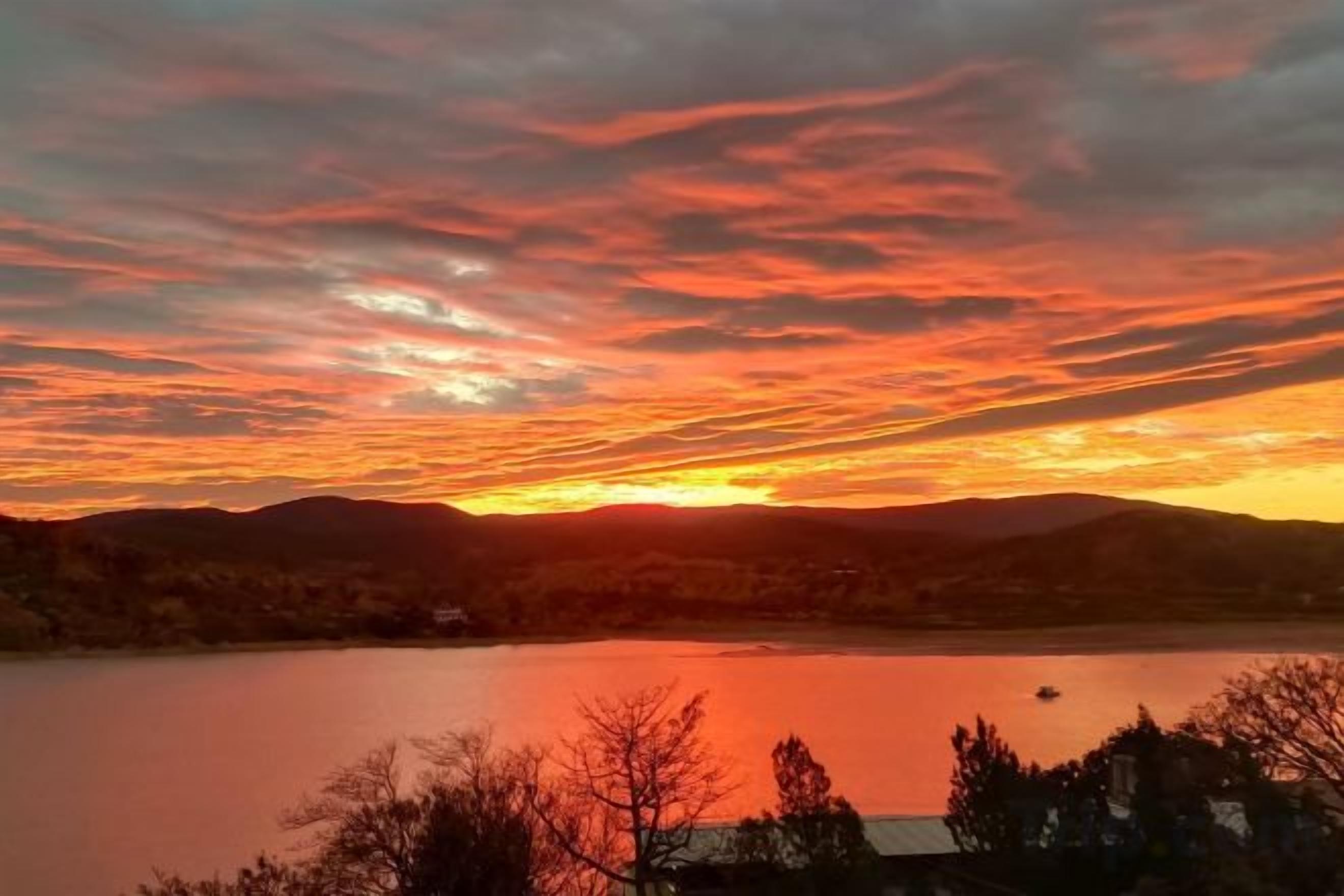 Ein Sonnenuntergang über einem See mit Hügeln im Hintergrund.