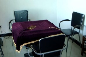 A room with a table covered by a dark cloth, two chairs, and a power outlet on the wall.