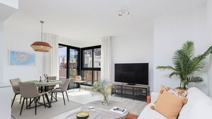 Una sala de estar moderna con comedor, televisor de pantalla plana y un amplio ventanal con vistas a la ciudad.