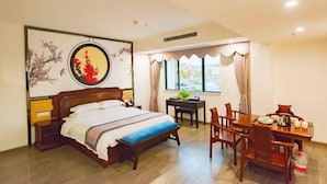 A hotel room with a bed, a dining table, chairs, a small table with a plant, and a window with curtains. - Tongjing Hotel (Renhua)